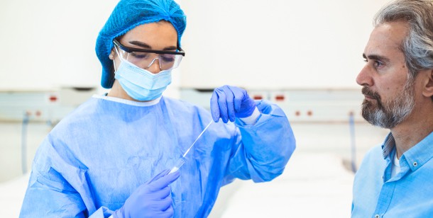 A doctor holds a COVID-19 test kit while a man sits next to her in an emergency room in Houston, TX