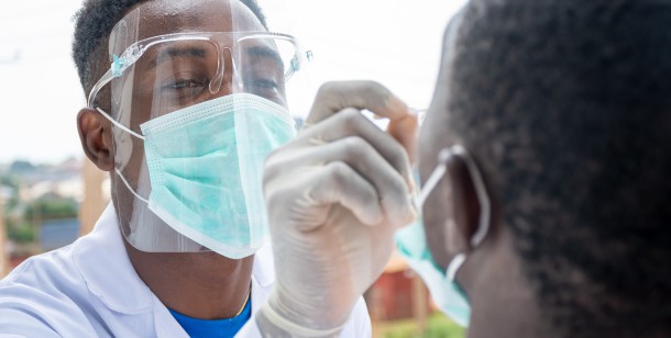 A doctor with a mask pulls down a patient's mask to swab his nose for COVID-19 outside of an emergency room in Houston, TX