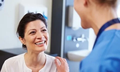 A female patient smiles at her doctor when visiting Village Emergency Centers in Houston, TX for her UTI