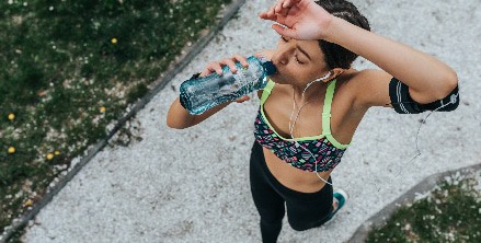 A woman drinks from a bottle of water as she exercises in Houston, TX