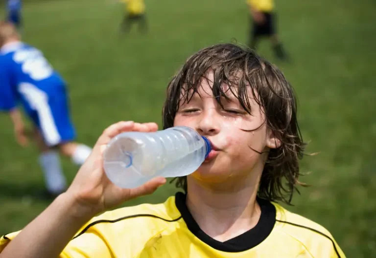 A thirsty child soccer player drinking water on the sidelines in Houston, TX