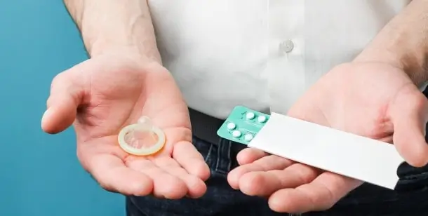 A man holds a condom and birth control pills in Houston, TX